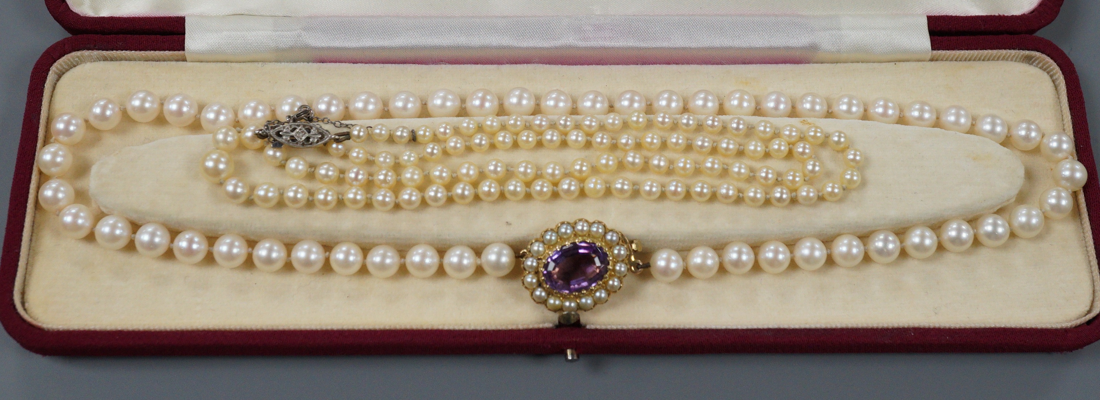 A modern single strand cultured pearl necklace, with 9ct, amethyst and cultured pearl set ova clasp, 44cm and one other single strand graduated cultured pearl necklace, with diamond chi set 9ct white gold clasp, 50cm.